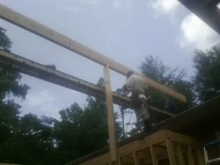 Carpenter setting a ridge beam over a new addition frame — Ice Dam Removal by Roofing Brothers in Syracuse