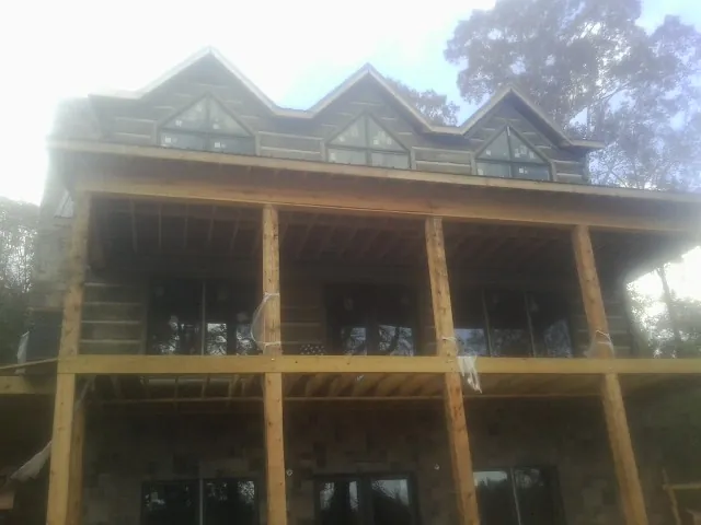 Dormers and porch framing on a large log home under construction — Roof Coating work by our crew in Syracuse