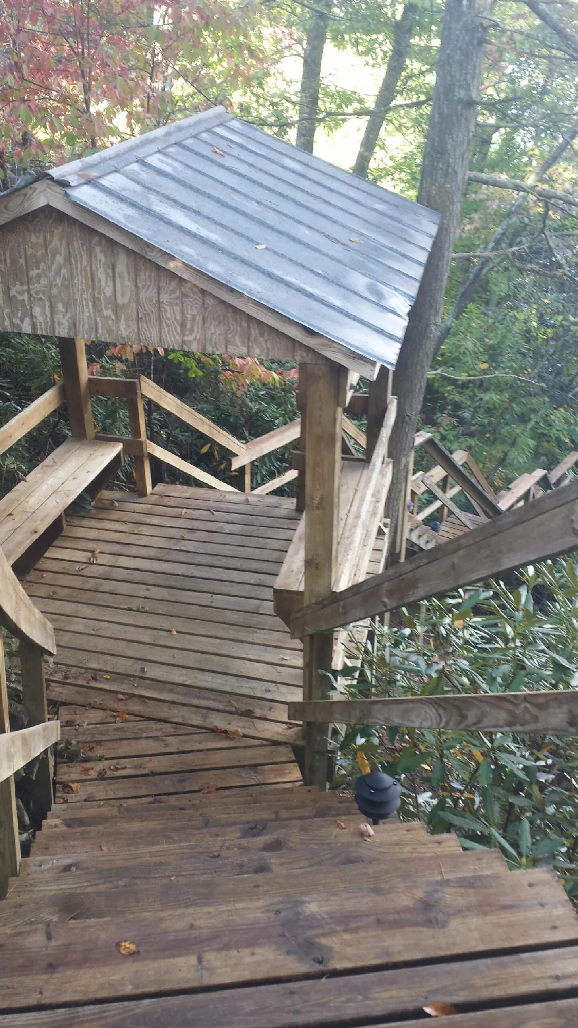 Metal roofed shelter over wooden steps on a wooded walkway — Skylight Repair & Installation work by our crew in Syracuse
