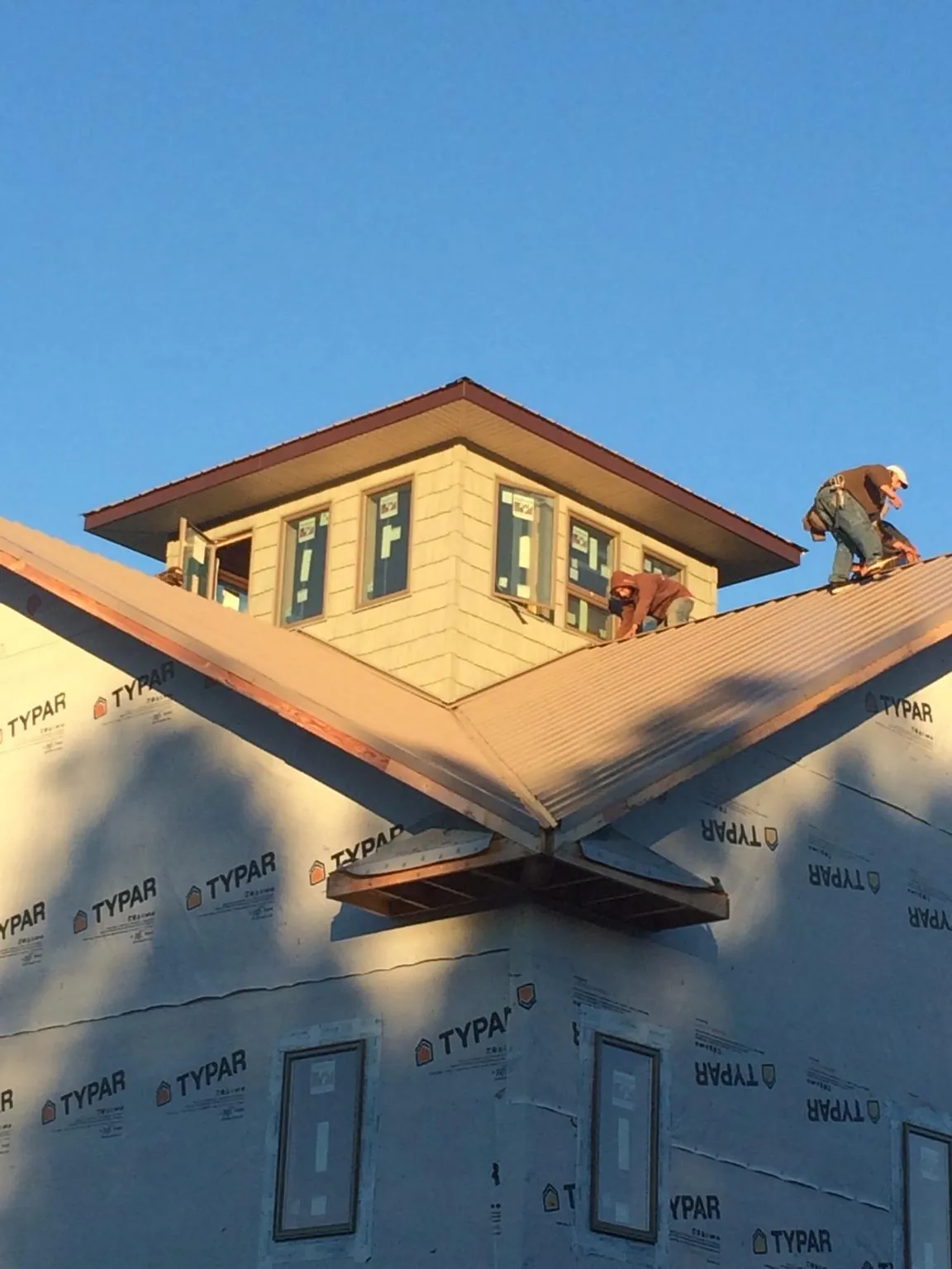 Roofers working around a rooftop cupola on a new metal roof at sunset — Roof Waterproofing in Syracuse by Roofing Brothers